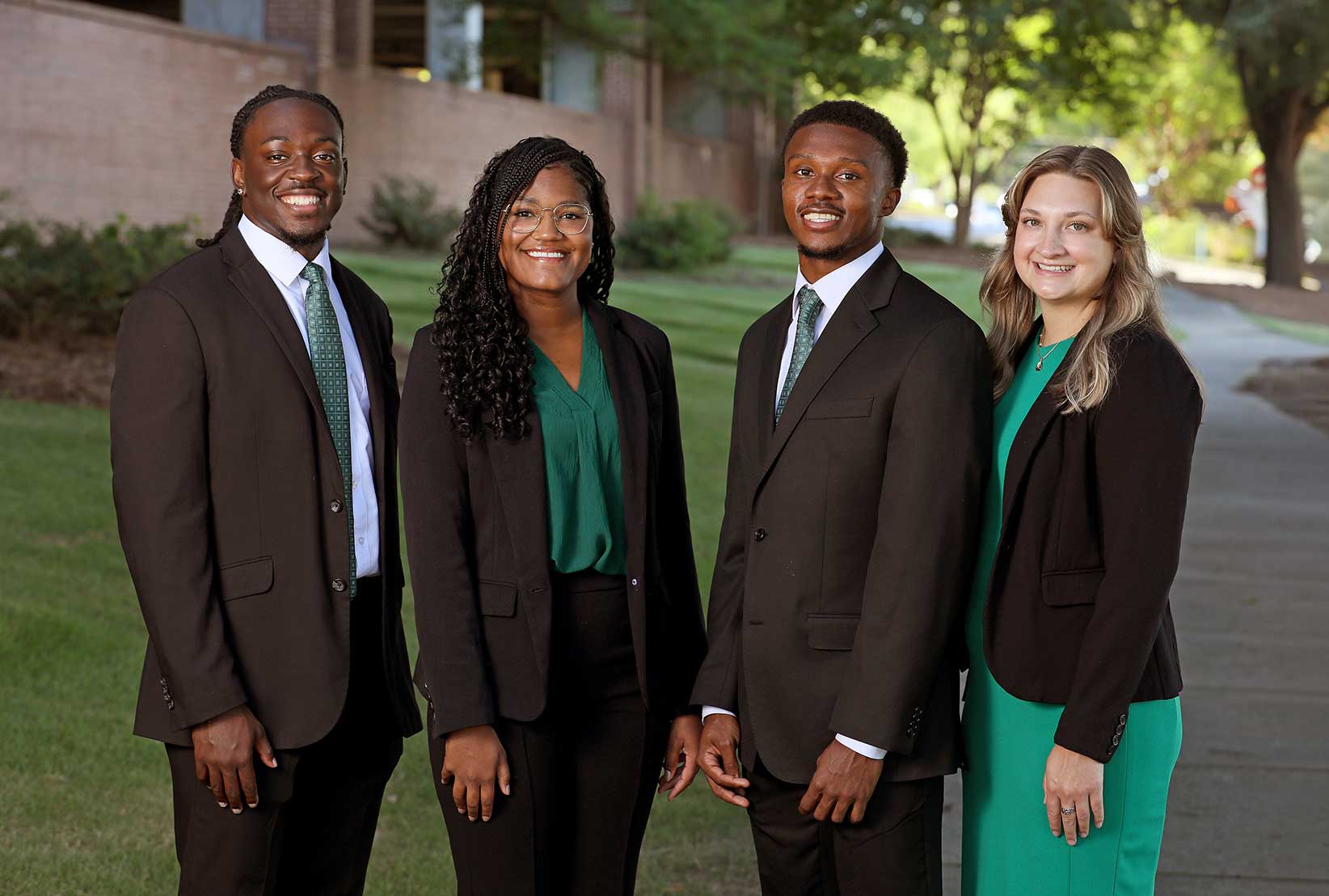 A group of smiling administrative fellows dressed in business attire.