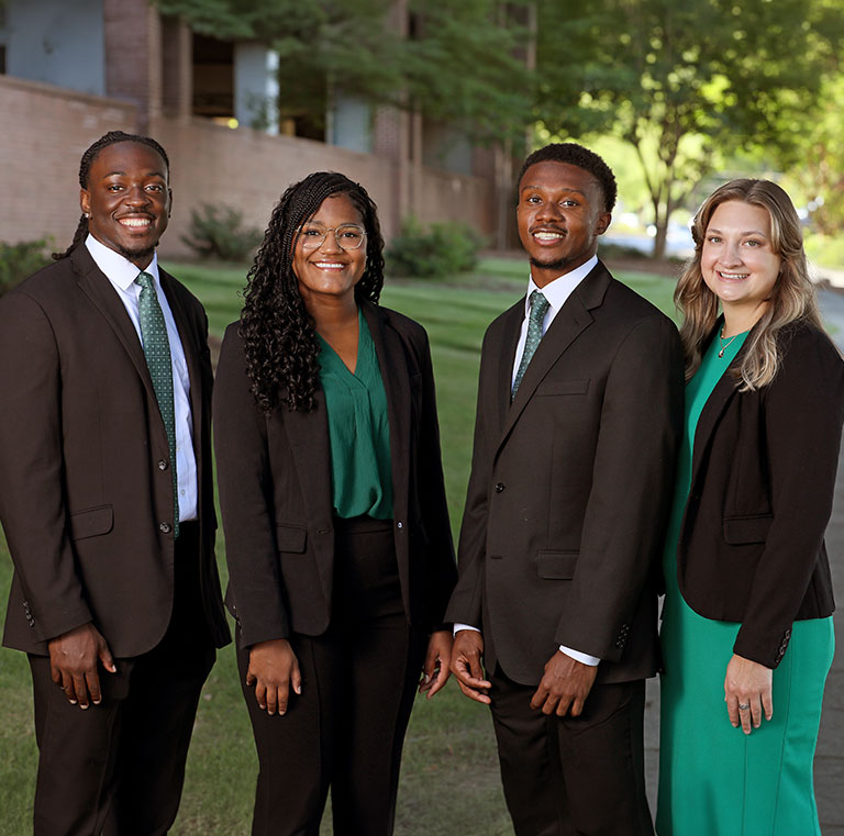 A group of smiling administrative fellows dressed in business attire.