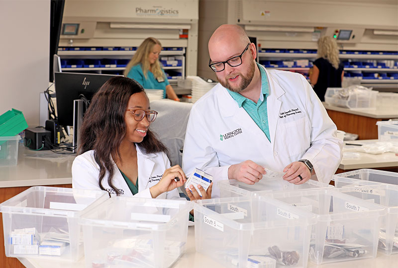 A pharmacist and resident work together to organize materials.