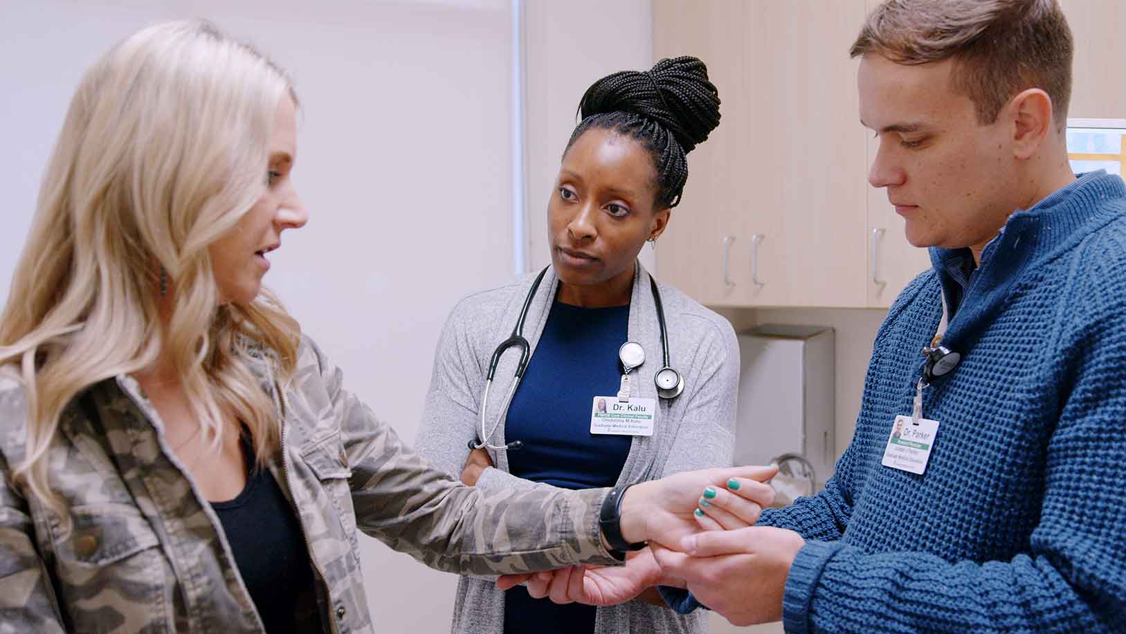 A doctor and a resident examine a patient's wrist.