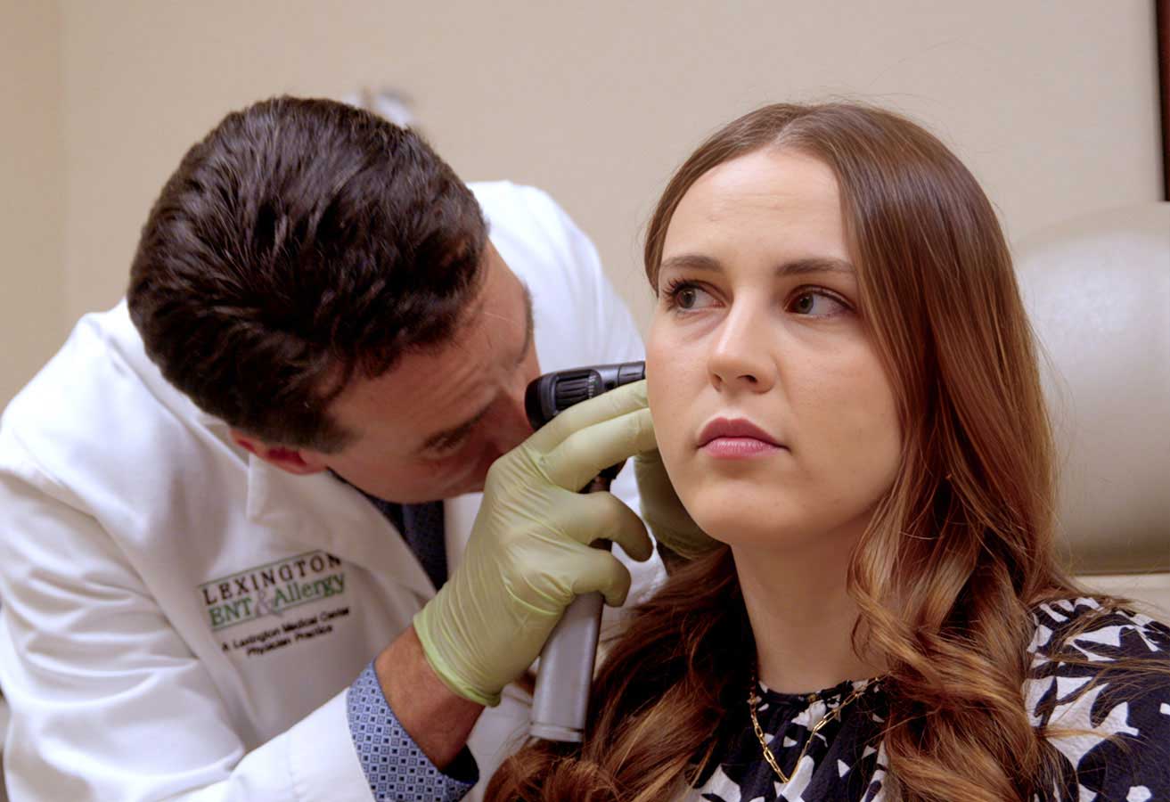 A doctor looking inside a female patient's ear.