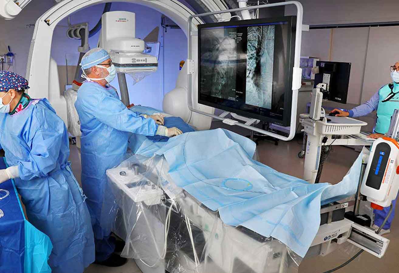 A team of doctors and nurses using imaging equipment on a patient.