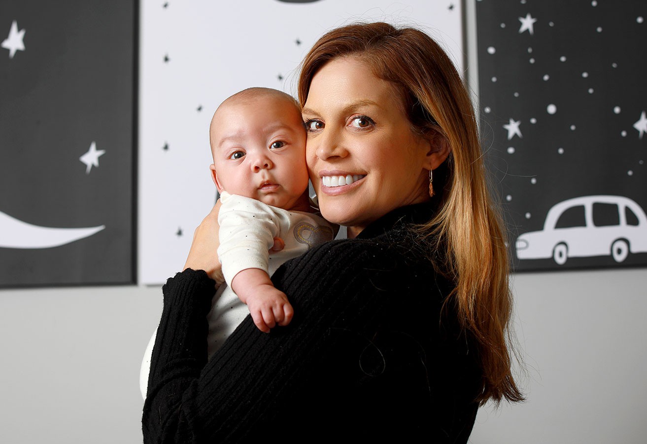 A smiling mother holding a baby. 